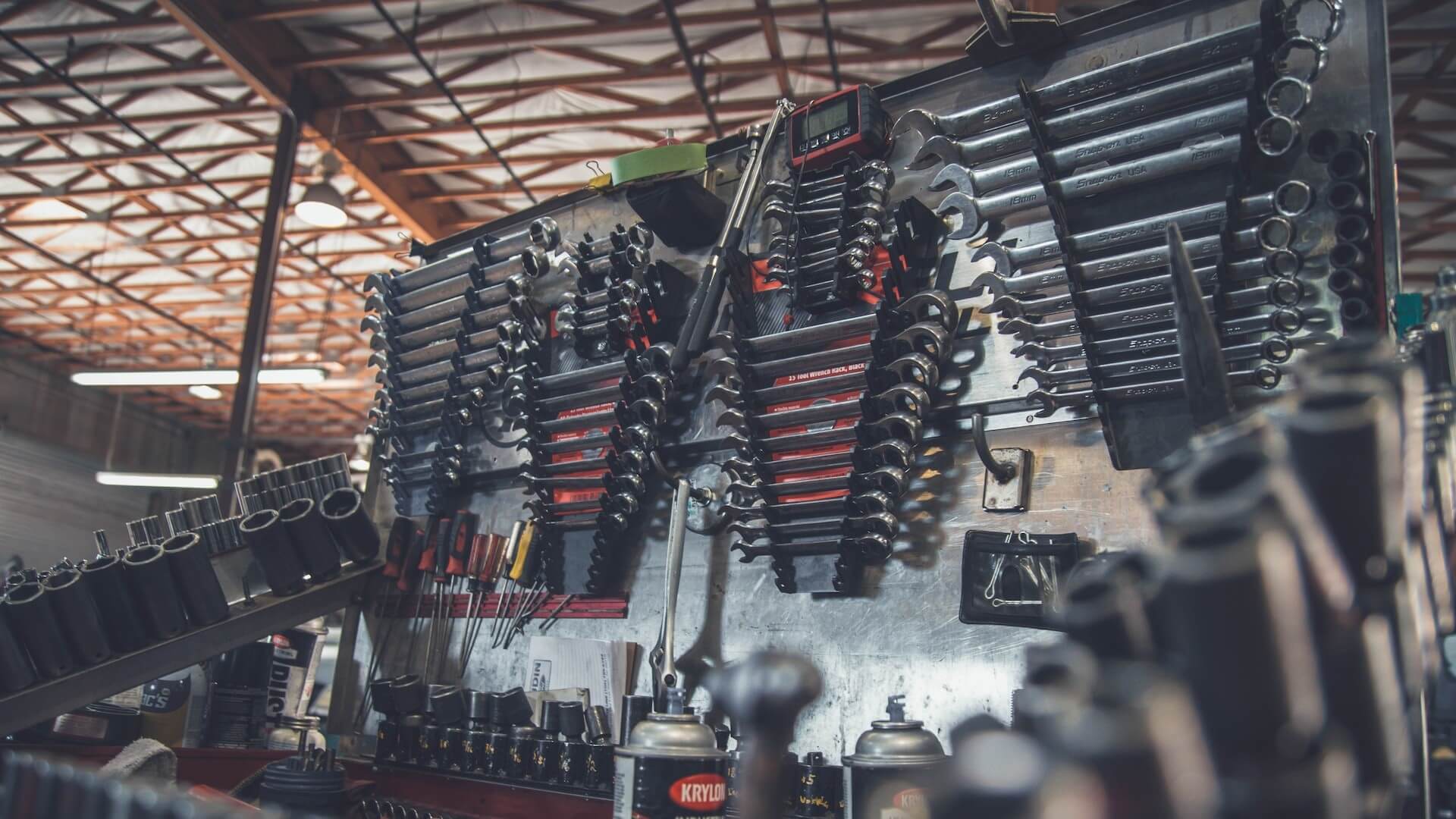 Una escena en el interior de un taller de reparación de automóviles, con herramientas, equipos y vehículos en mantenimiento o reparación.